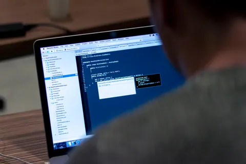 Softwareentwickler programmiert am Laptop im Dunkeln