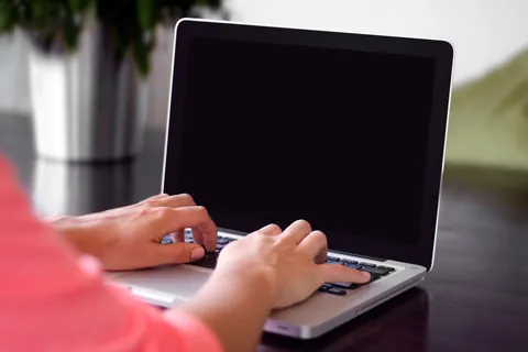 Hände tippen auf einer Laptop-Tastatur